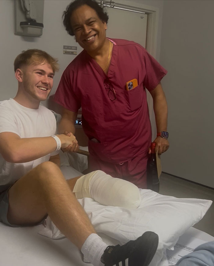Young man with leg amputation in hospital bed shaking hands with doctor after rock concert incident recovery.