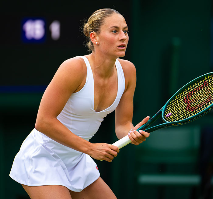 Female tennis player in white outfit focused during match amid testosterone remark controversy and rival&rsquo;s bikini photo response.