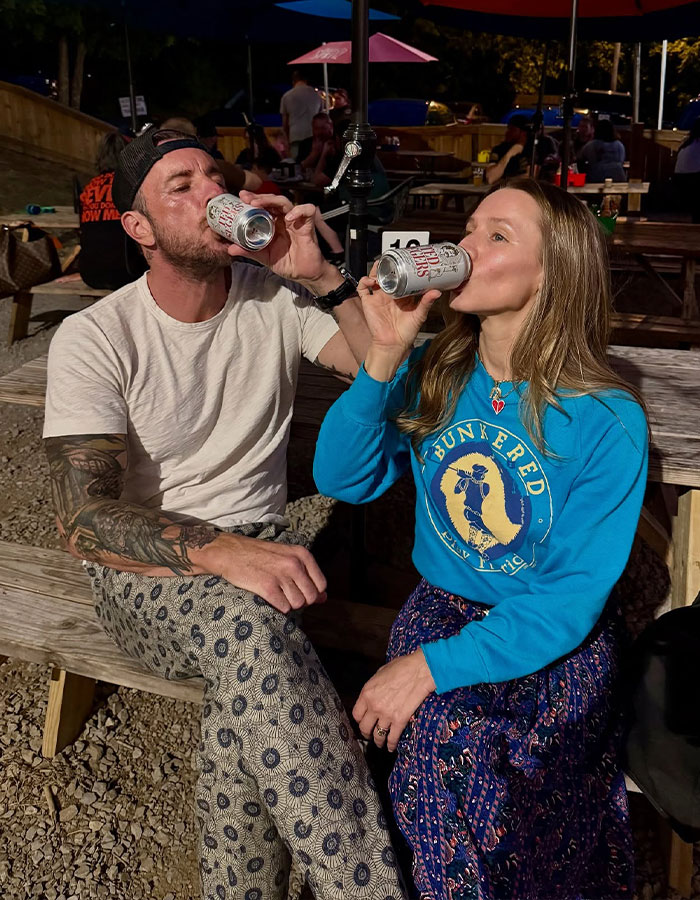 Kristen Bell and Dax Shepard sitting outdoors drinking from cans, enjoying a casual night out together. Kristen Bell and Dax Shepard sitting outdoors drinking from cans, enjoying a casual night out together.