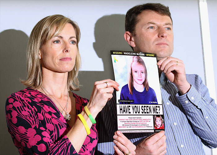 Woman holding a missing child poster related to Madeleine McCann during court testimony about identity clues.
