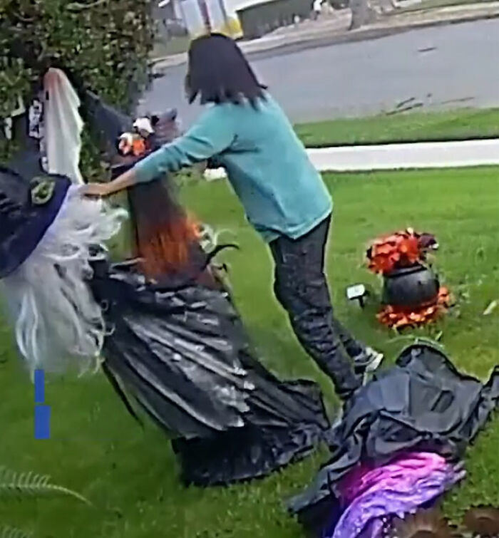 Woman attacking neighbor's Halloween witches decorations twice in bizarre viral footage on a grassy lawn.