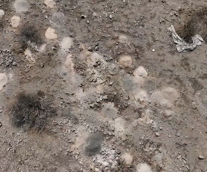 Aerial view of desert ground with scattered piles of rocks and dry bushes in Las Vegas desert investigation site. Aerial view of desert ground with scattered piles of rocks and dry bushes in Las Vegas desert investigation site.