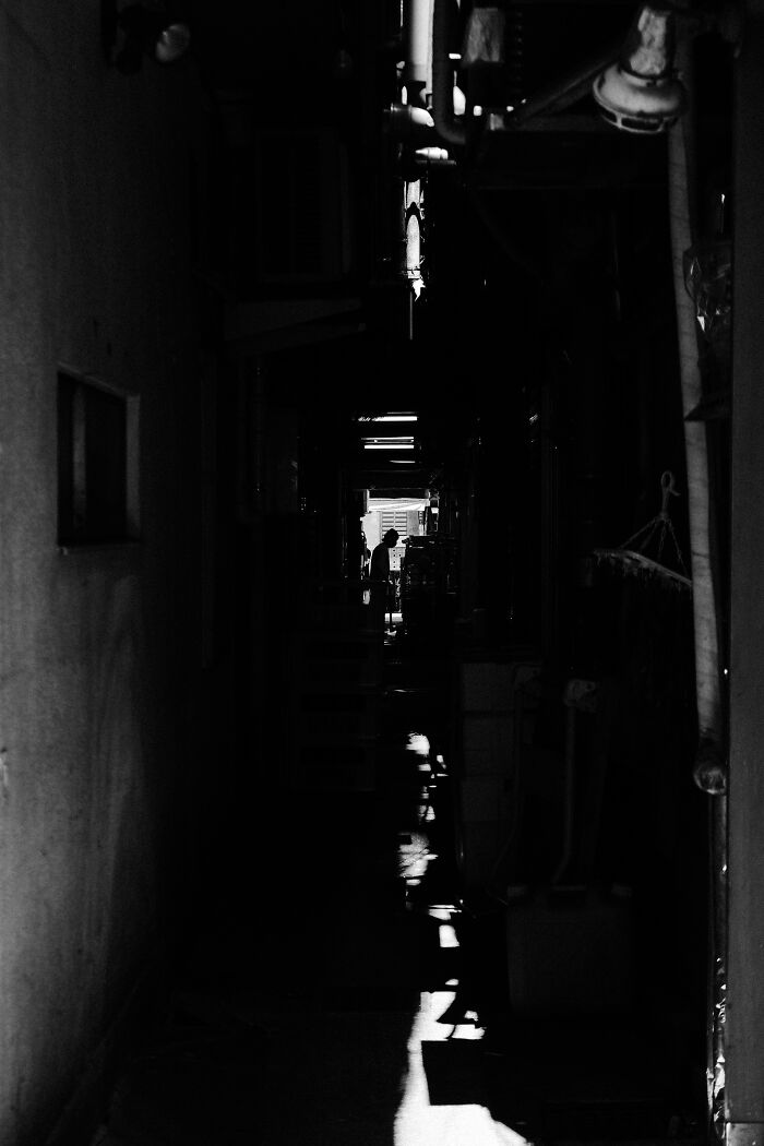 Dark narrow alley with silhouette of a person, showcasing stunning street photography capturing life’s unexpected moments.