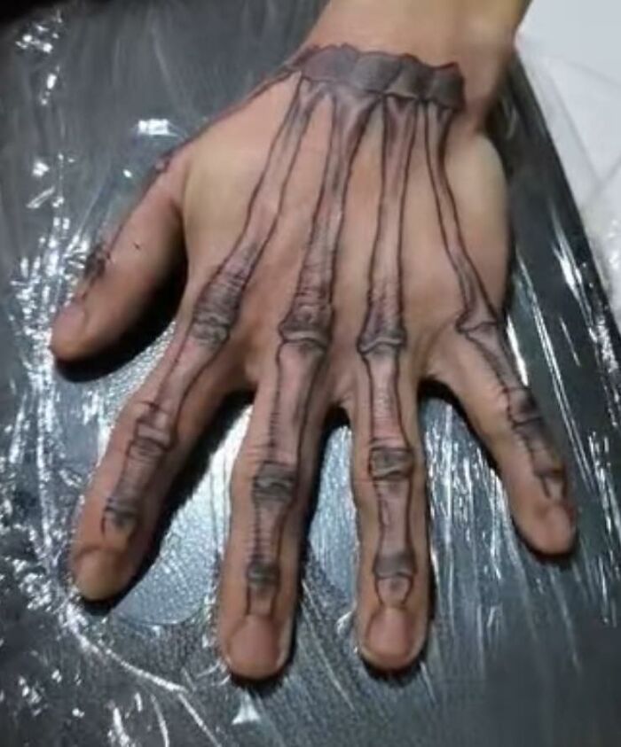 Hand tattoo showing realistic skeletal bones covering fingers and back of the hand, an unusual tattoo design.