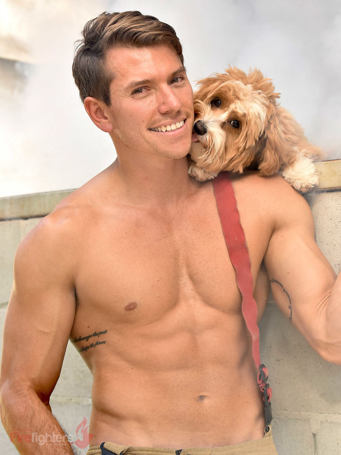 Shirtless firefighter smiling with an adorable dog resting on his shoulder in an Australian calendar photo.