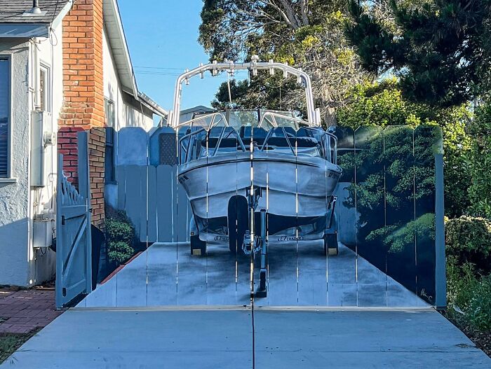 Driveway gate painted with a realistic boat and scenery, a clever example of petty revenge art to surprise neighbors.