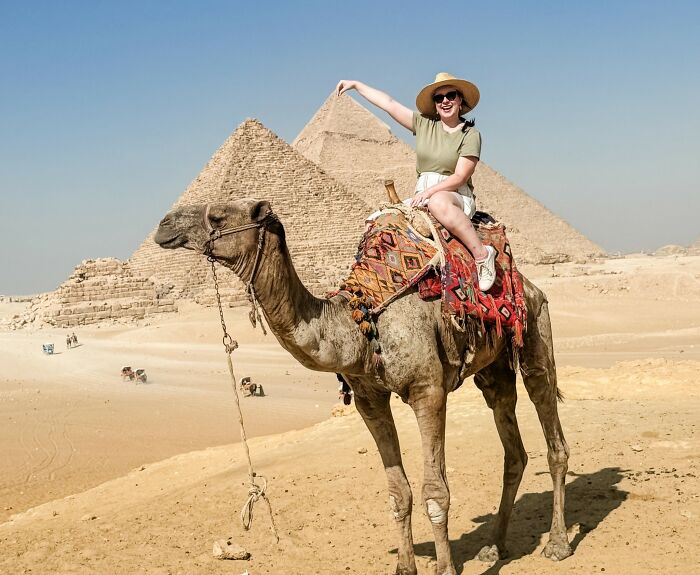 Woman in a hat riding camel near pyramids in desert, connected to Disney superfan news and major life update.