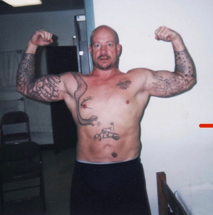 Shirtless man with tattoos flexing muscles indoors, representing America&rsquo;s most notorious jewel thief in a candid setting.