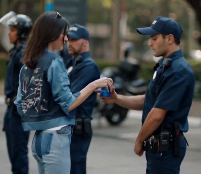 Kylie Jenner interacting with police officers in a staged scene amid controversy over fake arrest video and ICE raids response