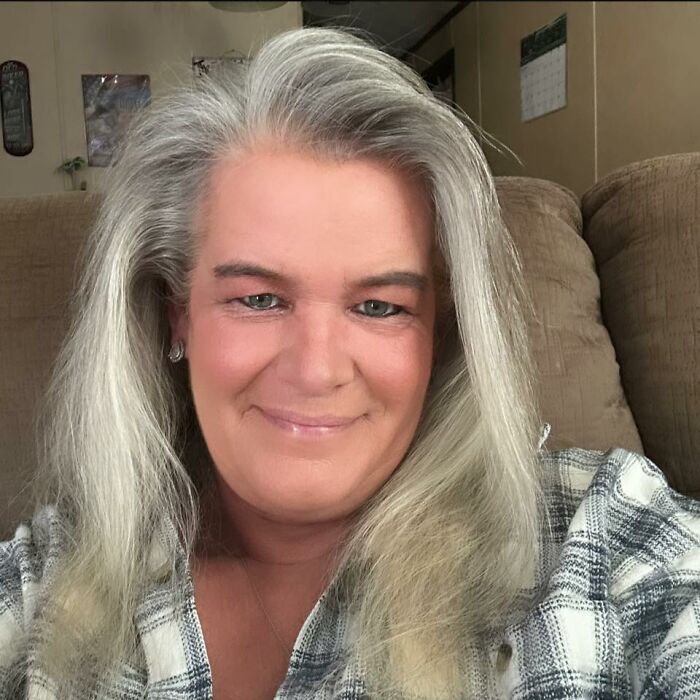 Middle-aged woman with gray hair smiling softly, showing emotional reaction after missing brother found alive in basement.