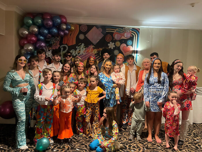 Large family group dressed in colorful outfits posing indoors after $70,000 Disney vacation causing court issues.