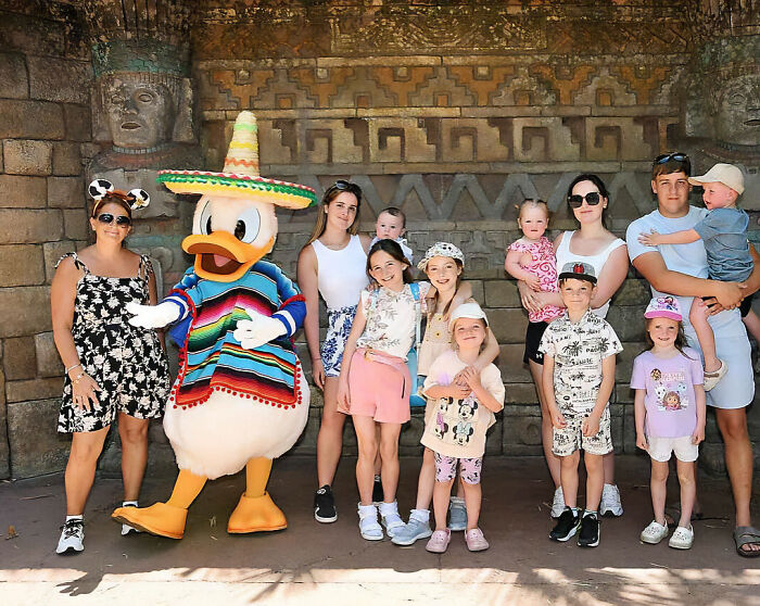 Family of 22 posing with Donald Duck at Disney during a $70,000 vacation that led to court issues.