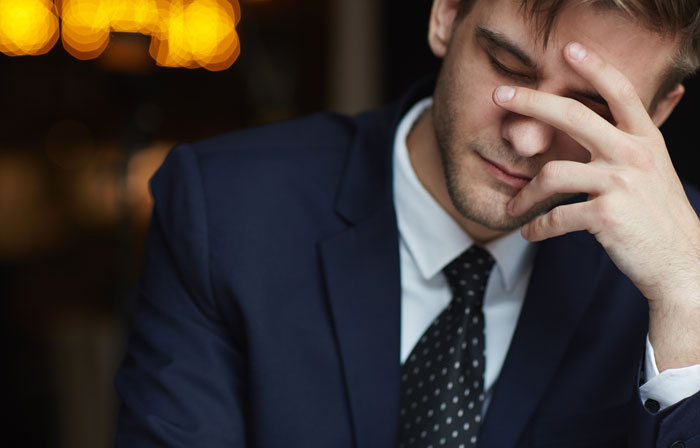 Young man in a suit looking stressed and upset, reacting to wedding sabotage by parents days before the ceremony.