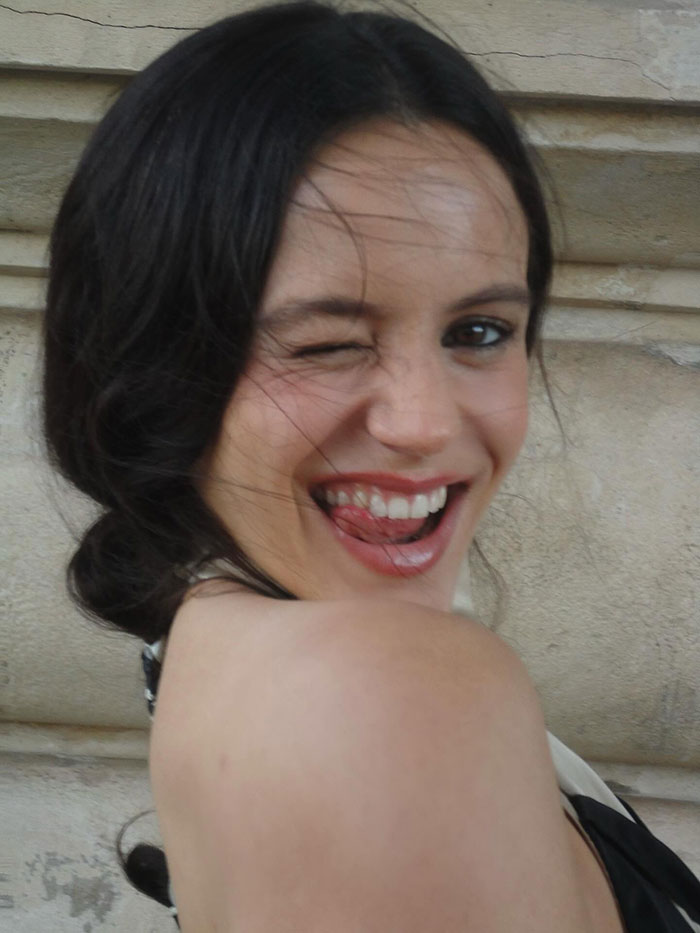 Pop star at Paris Fashion Week winking and smiling, highlighting her dyed armpit hair sparking mixed reactions.