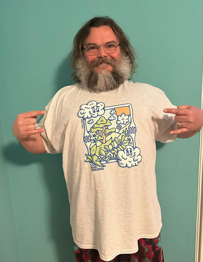 Man with glasses and long beard wearing a graphic t-shirt posing indoors, related to famous men shorter than fans imagined.