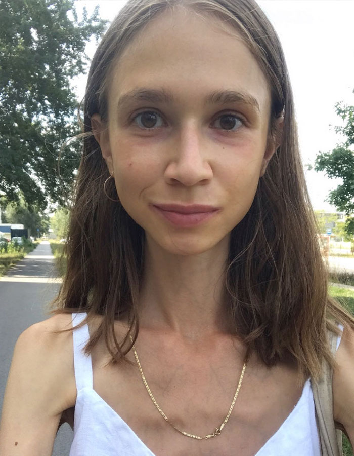 Vegan woman with long brown hair outdoors wearing white top and gold chain necklace on a sunny day. Vegan woman with long brown hair outdoors wearing white top and gold chain necklace on a sunny day.