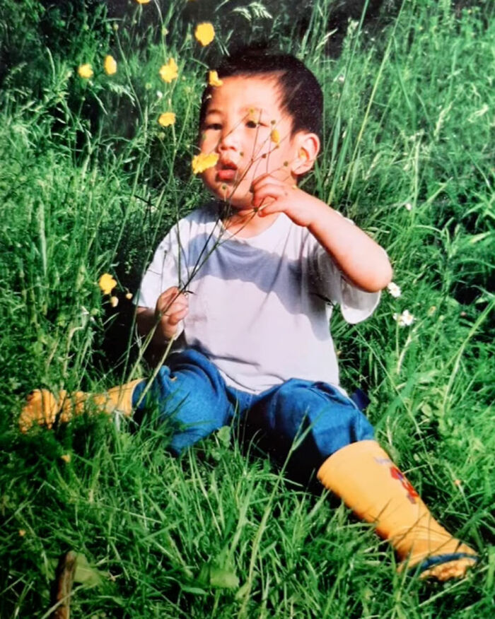 Young boy in yellow boots sitting in grass holding flowers, reflecting a thumbless man's genius life hacks and quirky humor. Young boy in yellow boots sitting in grass holding flowers, reflecting a thumbless man's genius life hacks and quirky humor.