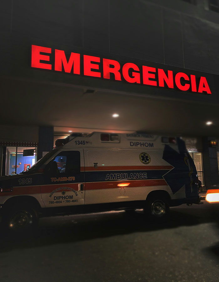 Emergency sign glowing red above ambulance parked outside hospital, symbolizing woman's act leaving boyfriend hospitalized.