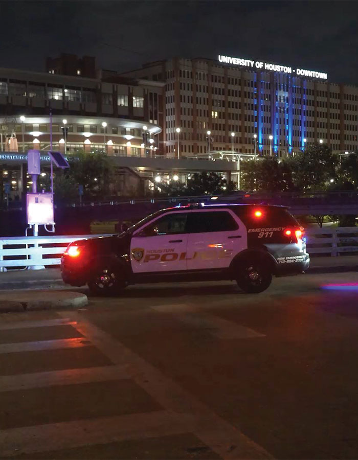 Houston police SUV with flashing lights at night near University of Houston downtown amid fears of serial criminal activity.