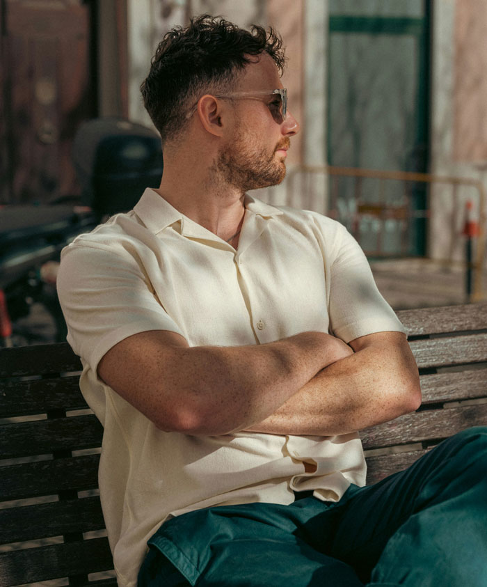 Man sitting on bench with arms crossed looking away, representing the most horrifyingly cruel person they’ve met.