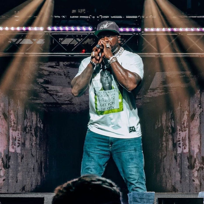 Performer on stage with microphone in hard rock cover of 50 Cent's Many Men amid AI music boom.