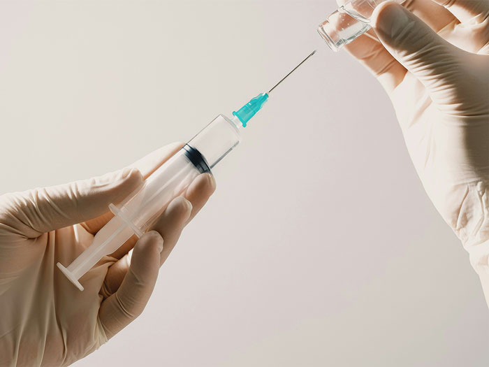 Gloved hands holding a syringe and vial, symbolizing medical procedures related to autopsy controversy.
