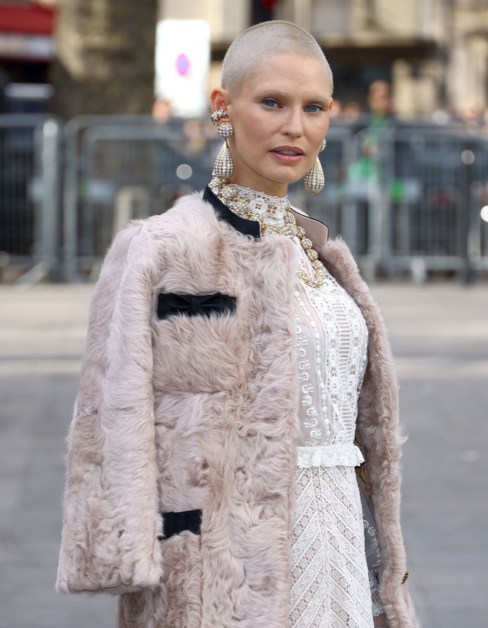 Former Victoria&rsquo;s Secret model with shaved head wearing fur coat and lace dress at a public event.