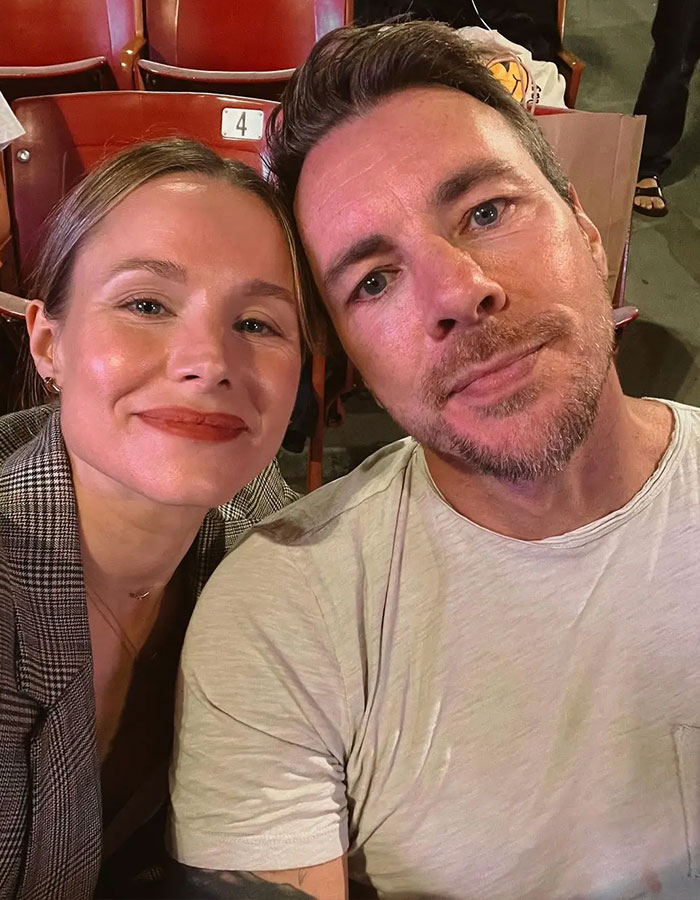 Kristen Bell and Dax Shepard taking a close-up selfie together while seated in a public venue. Kristen Bell and Dax Shepard taking a close-up selfie together while seated in a public venue.