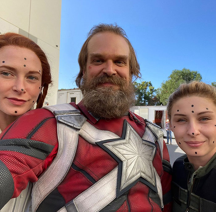 David Harbour in costume with two women marked for visual effects, related to viral interaction news.