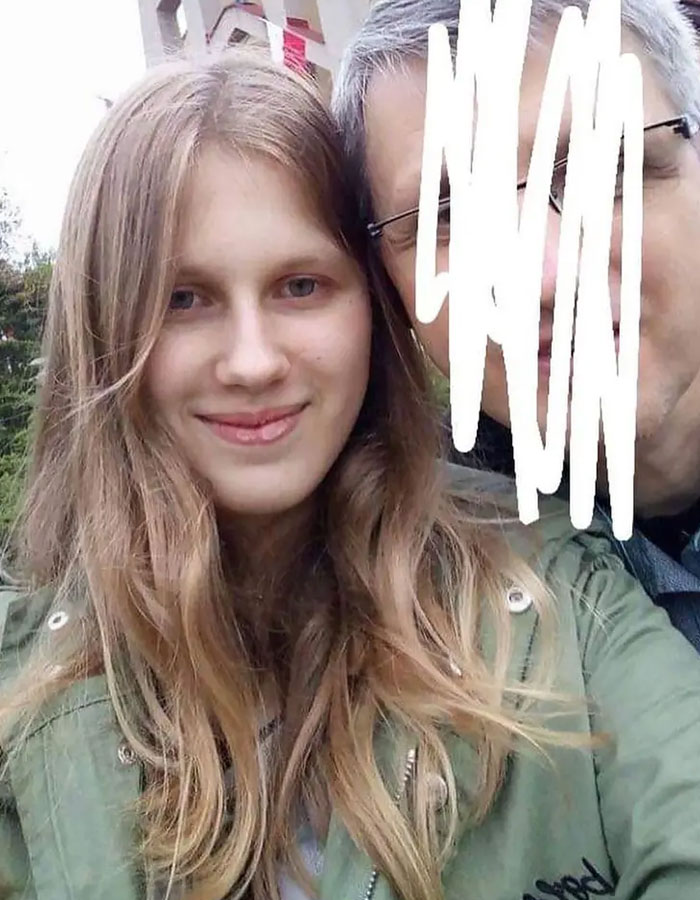 Young woman who believed she was Madeleine McCann, smiling, with a blurred person beside her outdoors.