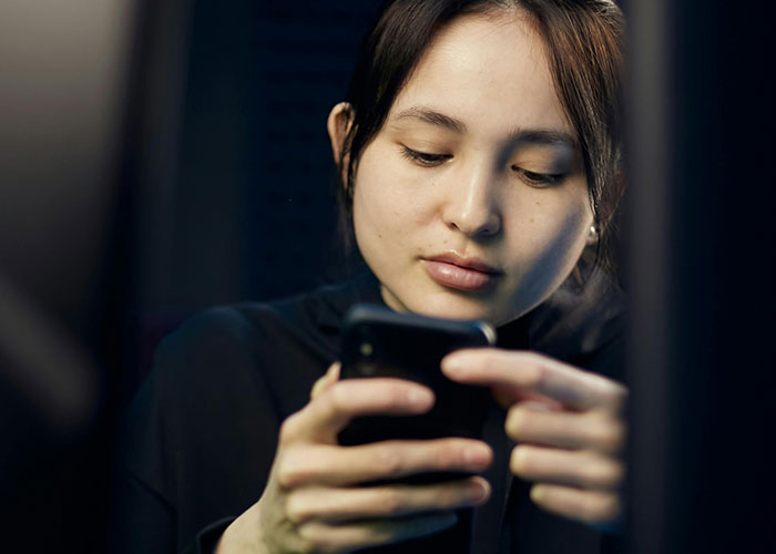 Young woman staring at her phone with a serious expression, capturing creepy things women said or did to men feelings.