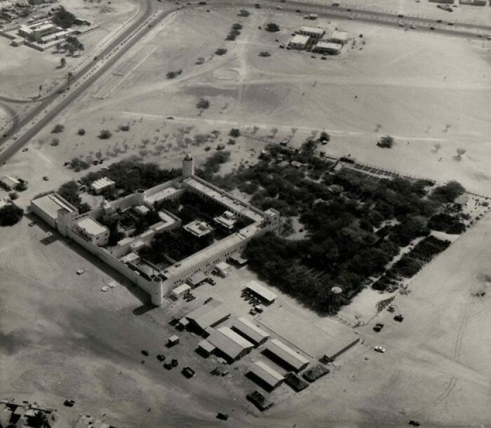 Aerial view of an old fortress surrounded by desert, showing a historical scene from world capitals before modern times.