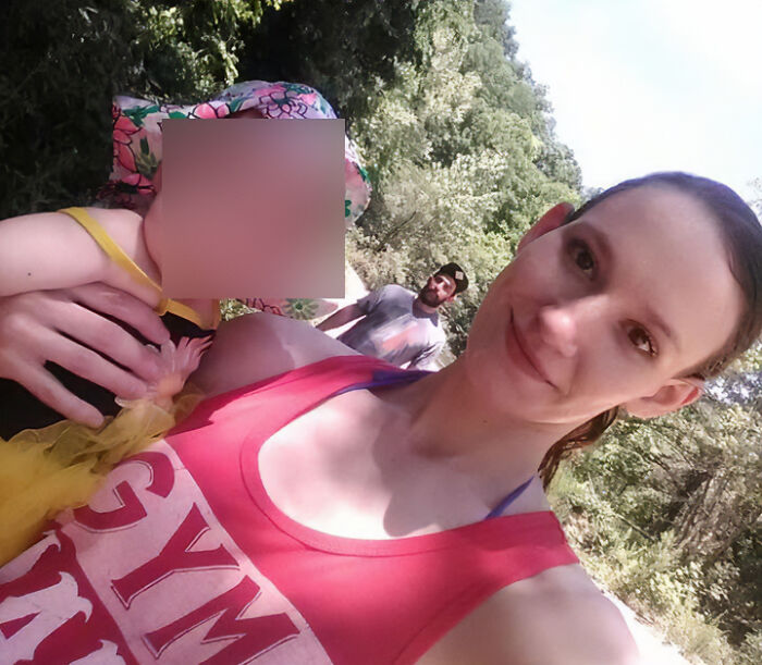 Woman smiling outdoors with child and man in background, representing friend with benefits situation.