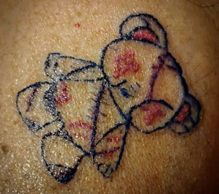 Tattoo of a poorly drawn teddy bear with red and black ink on skin, an unusual tattoo people allowed on their bodies.