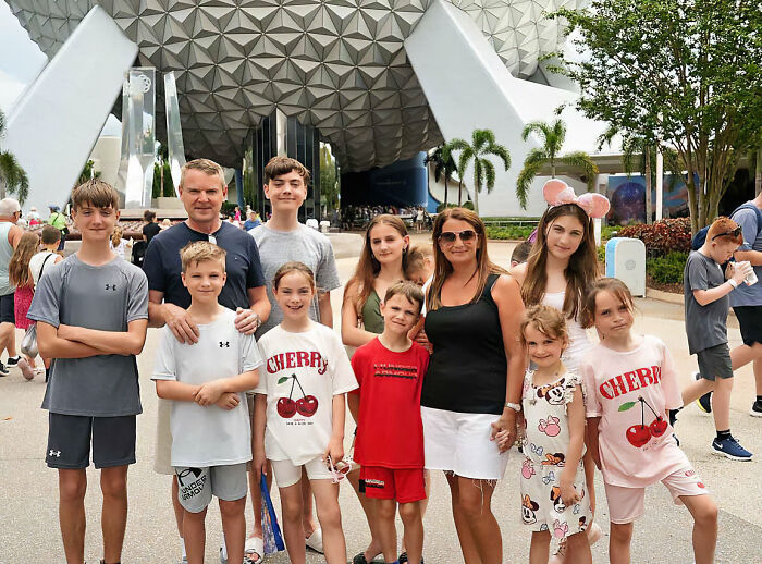 Large family posing for a group photo at a Disney theme park during a costly $70,000 Disney vacation dispute.