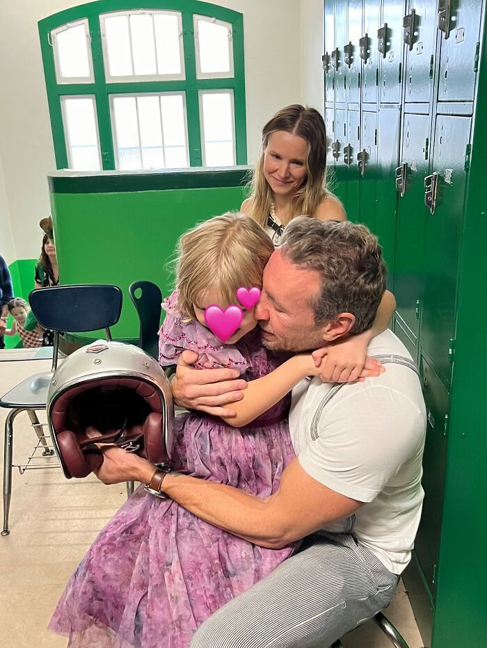 Kristen Bell celebrating wedding anniversary with family, holding a child in a purple dress near green lockers indoors.