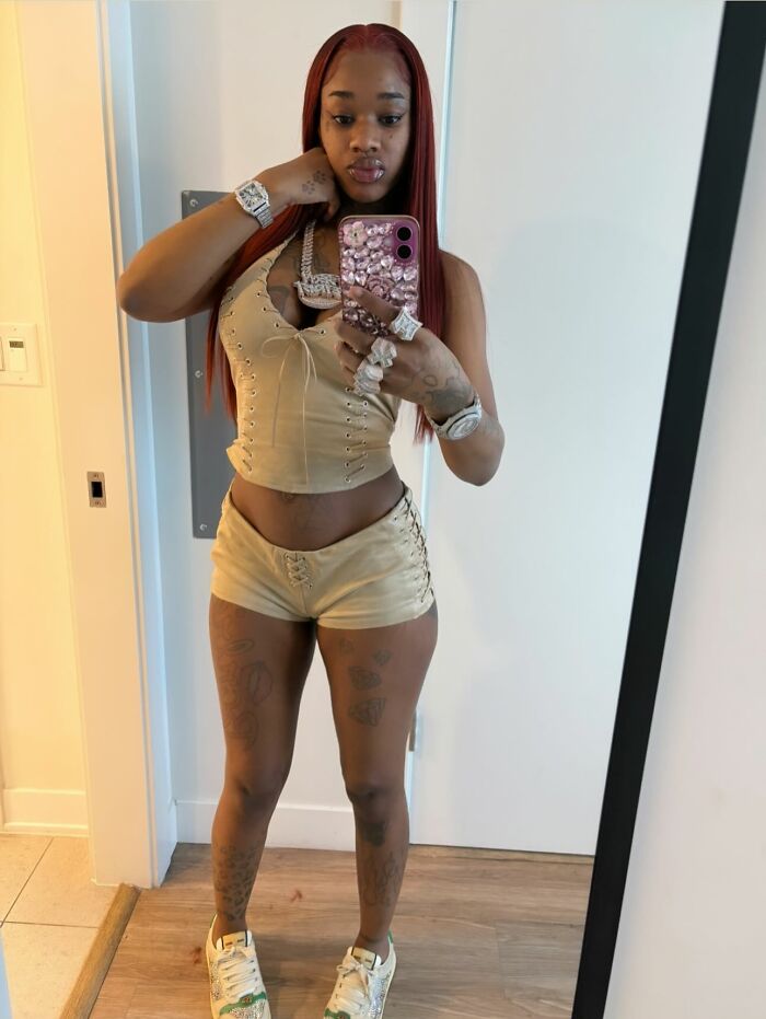 Rapper taking a mirror selfie wearing beige outfit and jewelry, related to red hat allegations and twerking controversy.