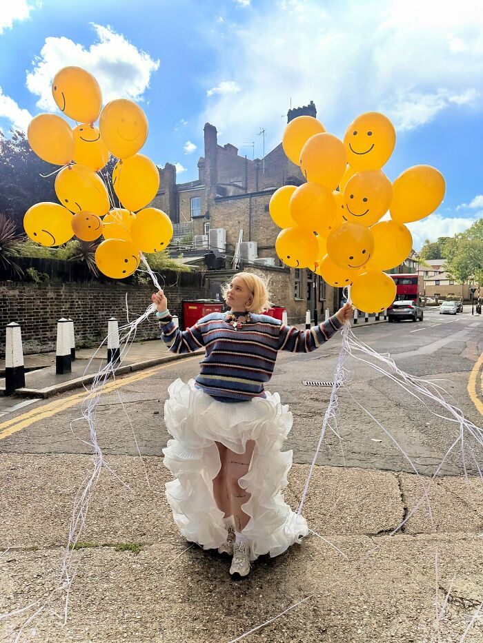 Pop star holding smiley face balloons outdoors, sparking fans' surprise over naming her son related to diabetes.
