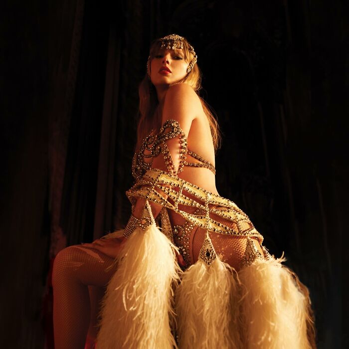 Taylor Swift wearing an ornate showgirl-inspired outfit with feathers, reflecting fan disappointment about new album expectations.