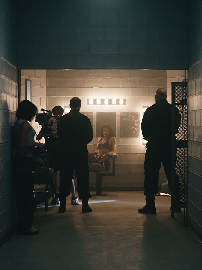Kylie Jenner during filming of fake arrest video inside a dimly lit interrogation room with crew and security present.