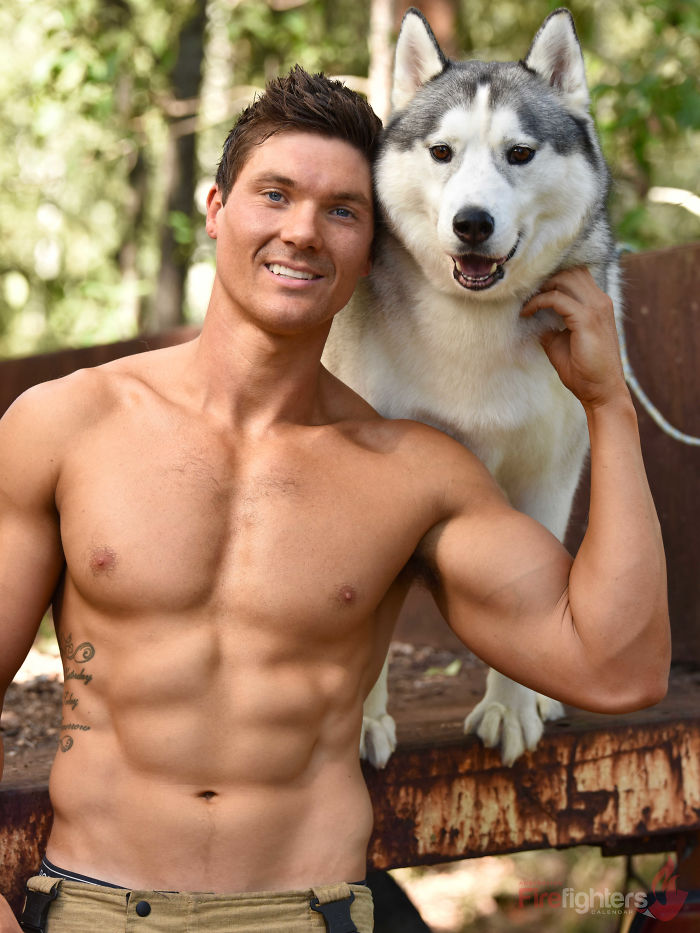 Shirtless firefighter posing outdoors with a friendly husky dog, featured in the Australian calendar photos.