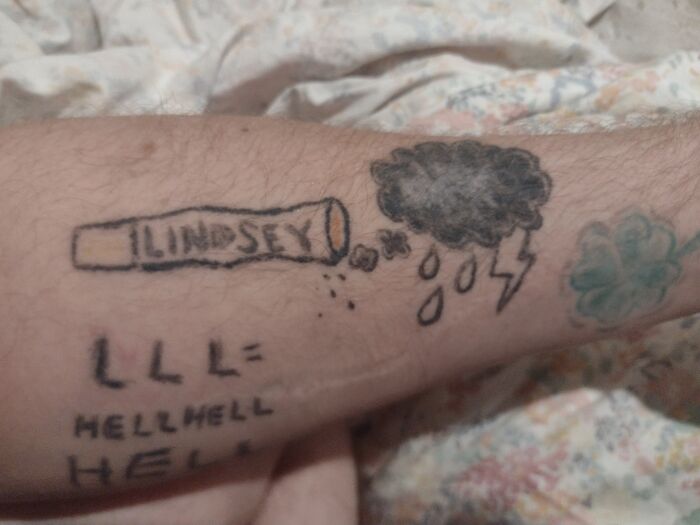 Arm tattoo featuring a crudely drawn cigarette labeled Lindsey, a dark rain cloud with raindrops and lightning, and text with misspelled words.