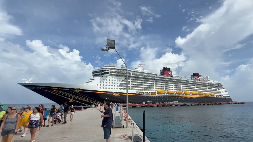 Disney cruise ship docked with passengers disembarking, related to mom's behavior leading to girl's ocean plunge incident.