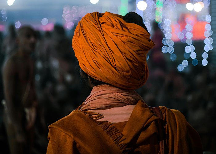 Person wearing an orange turban in a crowded event, illustrating moments when moms feel embarrassed by their kids.