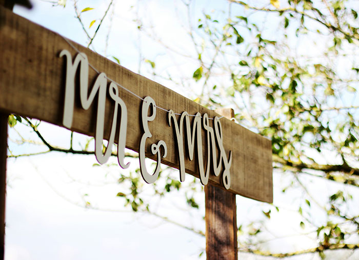 Wooden sign with Mr & Mrs letters hanging outdoors, related to marriage and UK health guidance controversy.