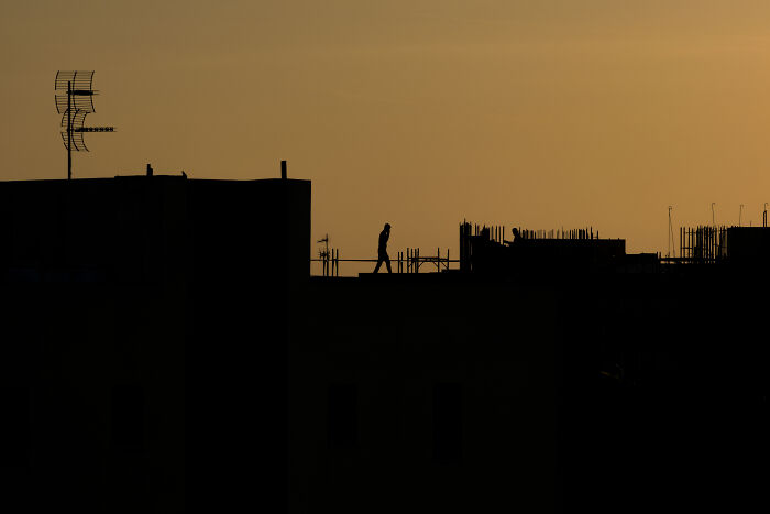 Silhouette of a person walking on a rooftop at sunset in a stunning street photography shot capturing unexpected moments.