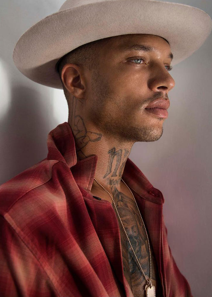 Man with tattoos wearing a beige hat and red shirt, showing the look of the world's hottest felon at 41 years old.