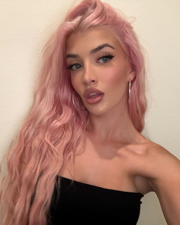 Charlie Sheen's daughter with long pink hair and hoop earrings posing, highlighting changes from plastic surgeries.