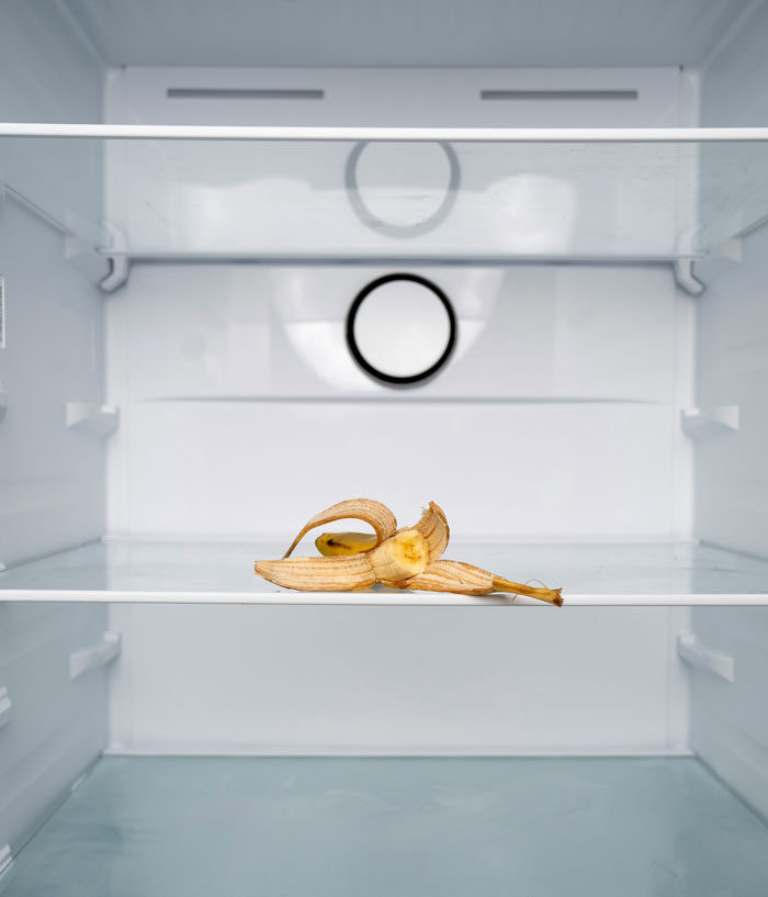 Partially peeled banana inside an empty fridge, symbolizing daycare workers discovering unexpected family secrets.