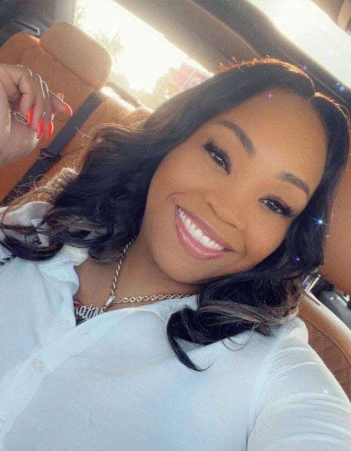 Young woman smiling inside a car, representing a woman's unhinged act after breaking into boyfriend&rsquo;s home incident.